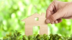 Hand touching house in grass Hand touching house in grass