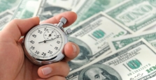 Man holding watch by pile of cash