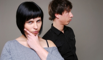 Woman pondering with aloof husband in background Woman pondering with aloof husband in background