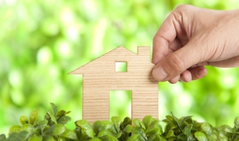 Hand touching house in grass Hand touching house in grass