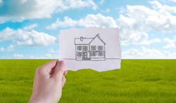 Imagining Home Hand holding picture of house to horizon