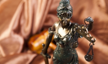 Blind Lady Justice statue with gavel in background Blind Lady Justice statue with gavel in background