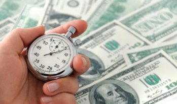 Man holding watch by pile of cash Man holding watch by pile of cash