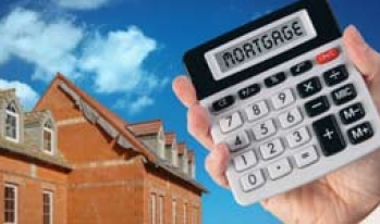 Hand holding a calculator in front of a house Hand holding a calculator in front of a house