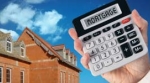 Hand holding a calculator in front of a house Hand holding a calculator in front of a house