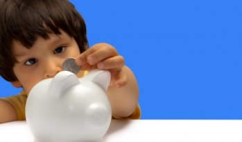 Child putting money piggy bank Child putting money piggy bank