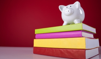 Piggy bank standing on college textbooks Piggy bank standing on college textbooks