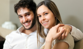 young couple together on the couch holding hands young couple together on the couch holding hands